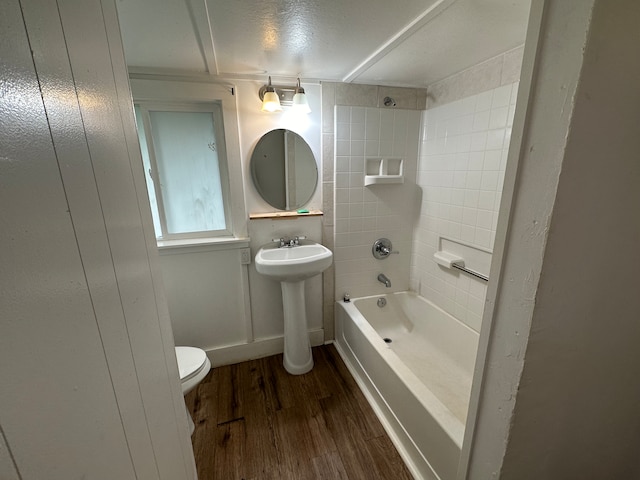 full bathroom with sink, wood-type flooring, tiled shower / bath combo, and toilet