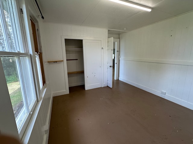 unfurnished bedroom featuring a closet and wooden walls