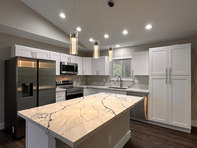 kitchen with a kitchen island, stainless steel appliances, sink, light stone countertops, and white cabinets