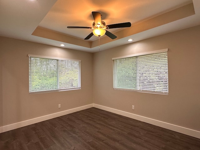 spare room featuring a tray ceiling, dark hardwood / wood-style floors, and ceiling fan