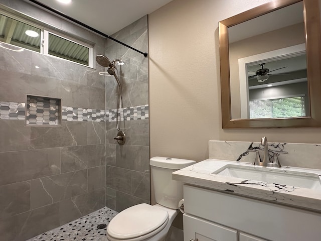 bathroom featuring vanity, ceiling fan, toilet, and tiled shower