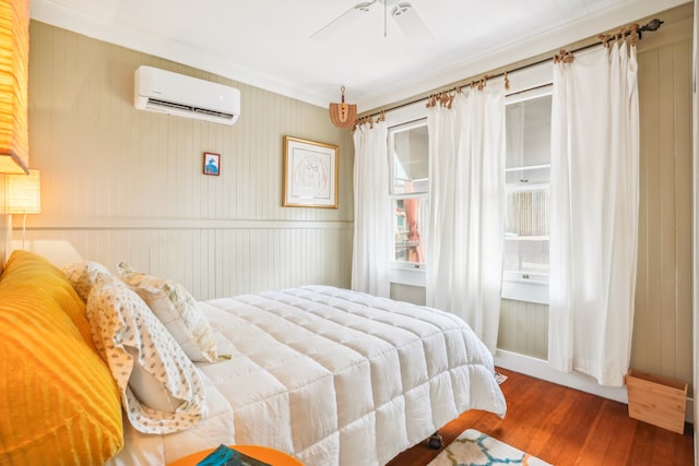 bedroom with ornamental molding, a wall mounted AC, hardwood / wood-style flooring, and ceiling fan