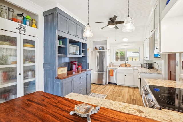 kitchen with appliances with stainless steel finishes, light hardwood / wood-style flooring, white cabinetry, and decorative light fixtures