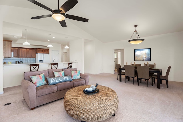 carpeted living room with ceiling fan and vaulted ceiling