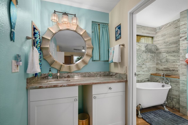 bathroom with vanity, a tub, tile walls, and hardwood / wood-style floors