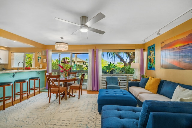 living room featuring a healthy amount of sunlight, wood-type flooring, track lighting, and ceiling fan with notable chandelier