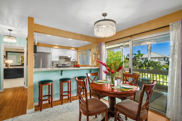 dining room with sink, a notable chandelier, and light hardwood / wood-style flooring