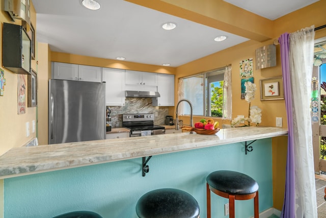 kitchen with extractor fan, a breakfast bar, stainless steel appliances, and kitchen peninsula