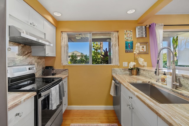 kitchen featuring appliances with stainless steel finishes, sink, light wood-type flooring, backsplash, and white cabinets