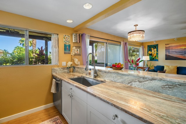 kitchen featuring white cabinetry, light hardwood / wood-style flooring, dishwasher, decorative light fixtures, and sink