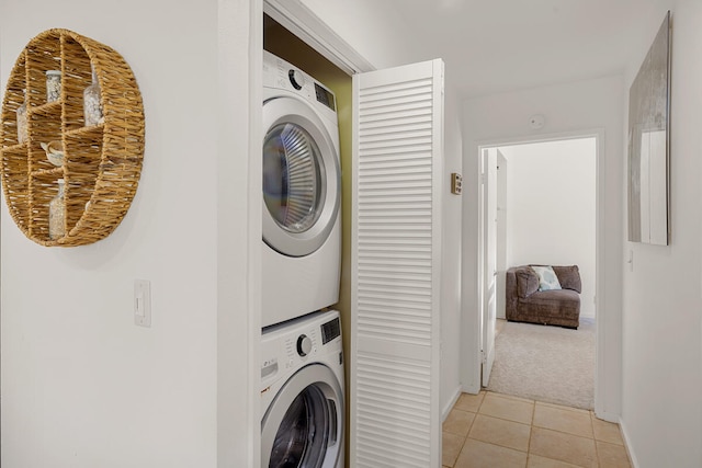 clothes washing area with stacked washer / drying machine and light tile patterned floors