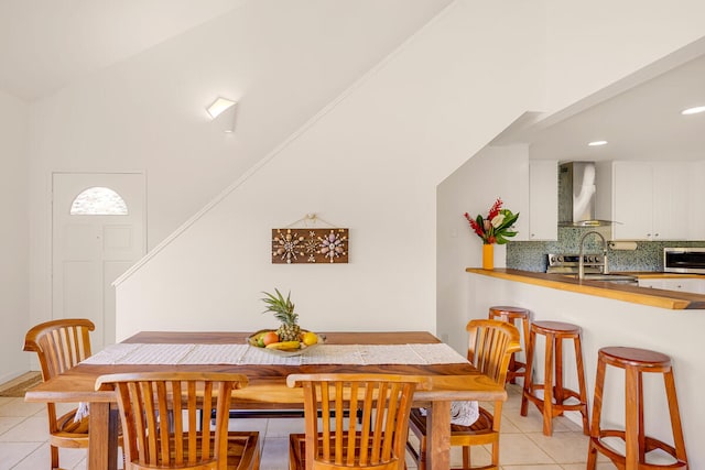 tiled dining area featuring crown molding and vaulted ceiling