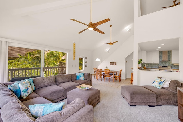 carpeted living room with beamed ceiling, sink, high vaulted ceiling, and ceiling fan