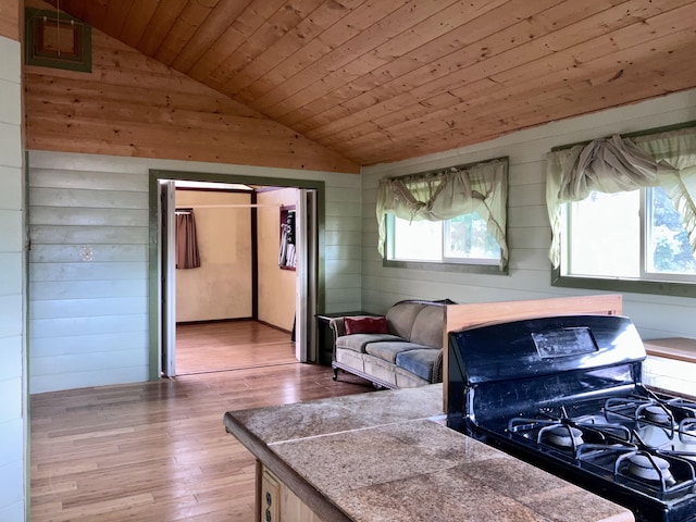 kitchen with lofted ceiling, wood ceiling, gas stove, wood walls, and light wood-type flooring