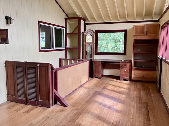 unfurnished office with light wood-type flooring and lofted ceiling with beams