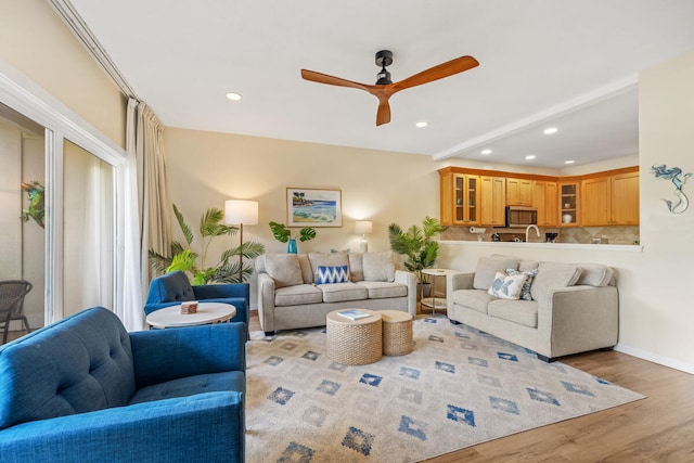 living room featuring beam ceiling, ceiling fan, and light hardwood / wood-style flooring