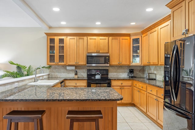 kitchen featuring kitchen peninsula, black appliances, sink, light tile patterned floors, and a breakfast bar