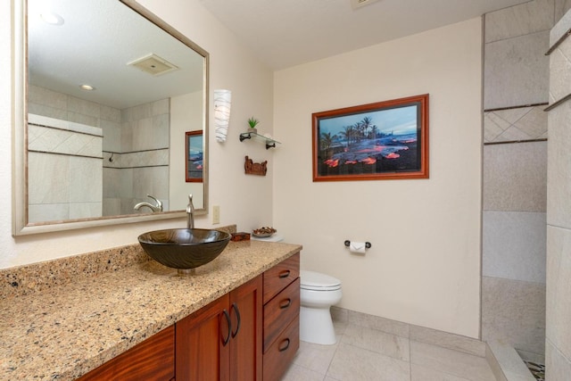 bathroom featuring vanity, tile patterned floors, toilet, and a tile shower