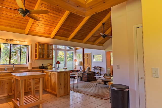 kitchen with beam ceiling, a healthy amount of sunlight, sink, and light tile patterned flooring