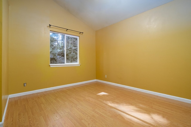 spare room with wood-type flooring and lofted ceiling