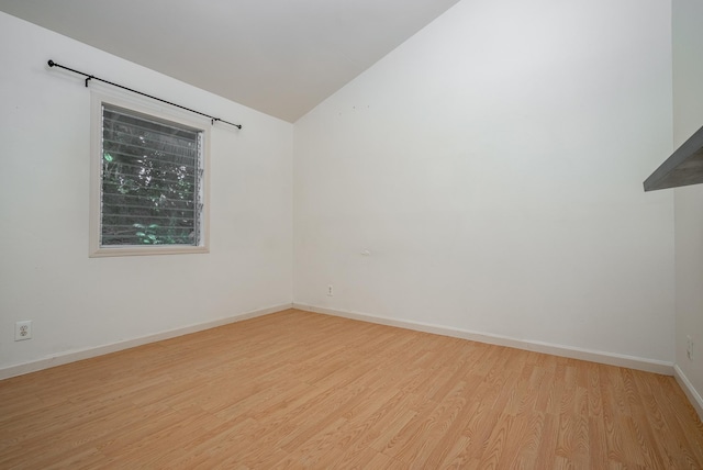 empty room with light wood-type flooring and vaulted ceiling