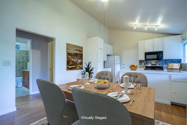 dining area featuring wood-type flooring, track lighting, and high vaulted ceiling