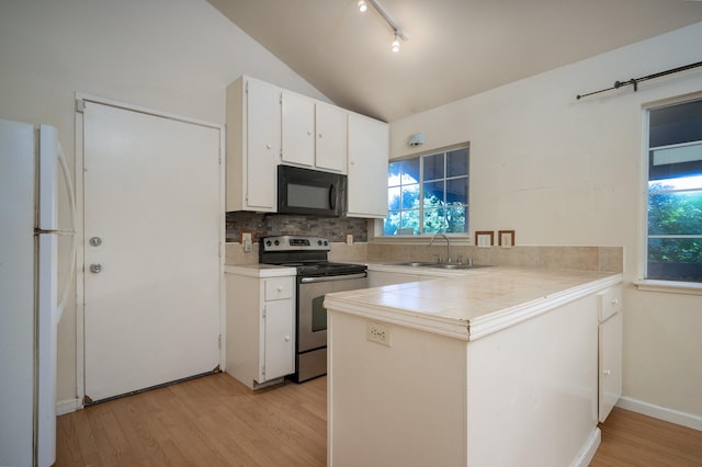 kitchen featuring stainless steel electric range, white refrigerator, sink, vaulted ceiling, and white cabinetry