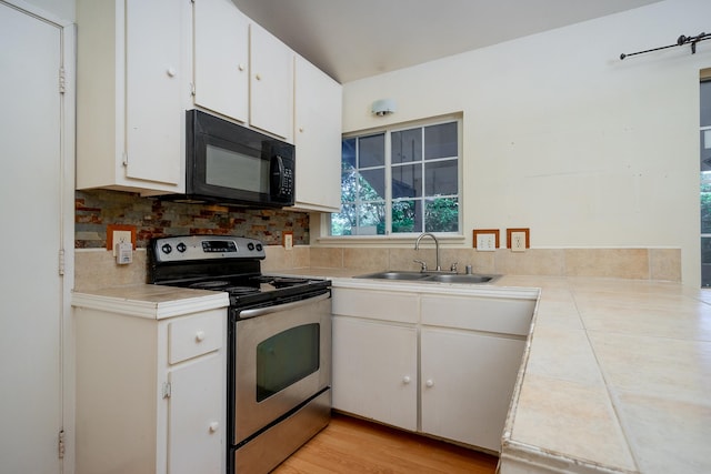 kitchen featuring tile countertops, electric stove, sink, light wood-type flooring, and white cabinetry