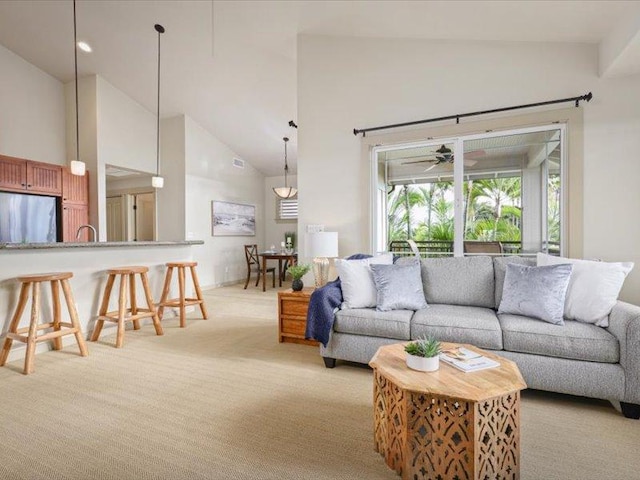 living room with high vaulted ceiling, light colored carpet, and a ceiling fan