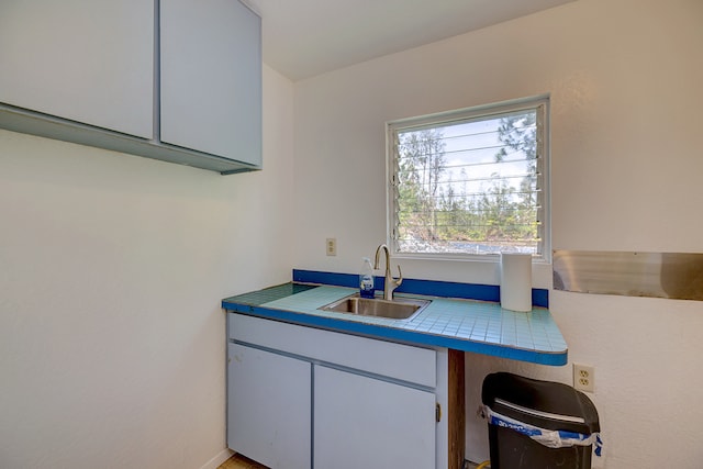 interior space with tile countertops and sink