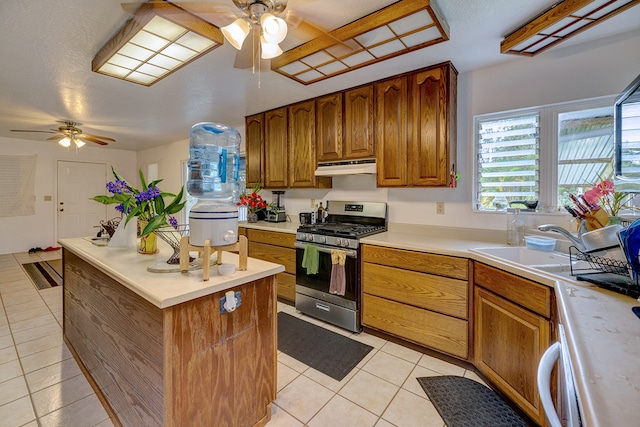 kitchen with sink, light tile patterned flooring, stainless steel range with gas stovetop, a textured ceiling, and ceiling fan