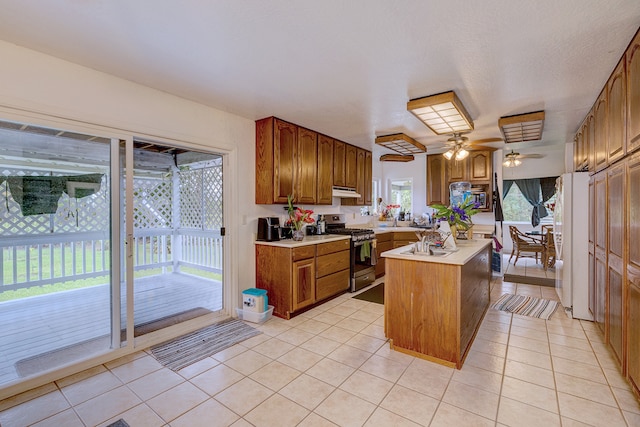 kitchen featuring a center island, light tile patterned floors, plenty of natural light, and stainless steel range with gas stovetop