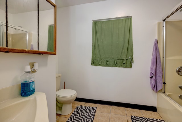 bathroom with combined bath / shower with glass door, toilet, and tile patterned flooring