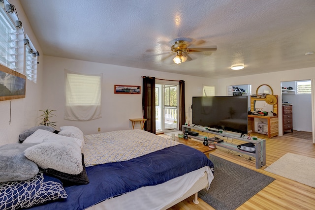 bedroom with multiple windows, a textured ceiling, wood-type flooring, and ceiling fan