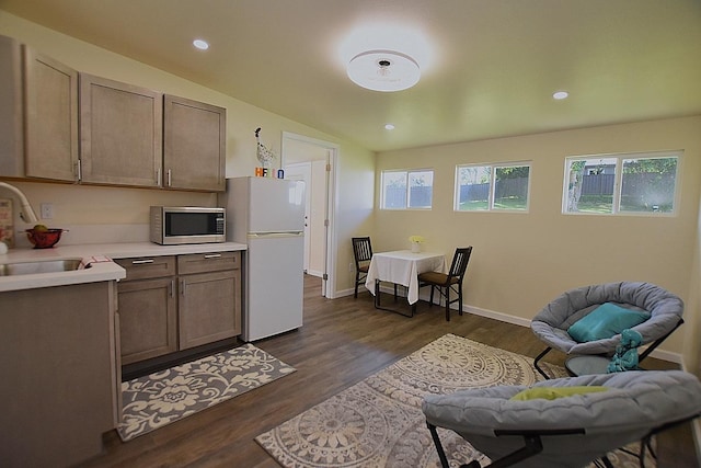 kitchen with sink, white fridge, dark wood-type flooring, and vaulted ceiling