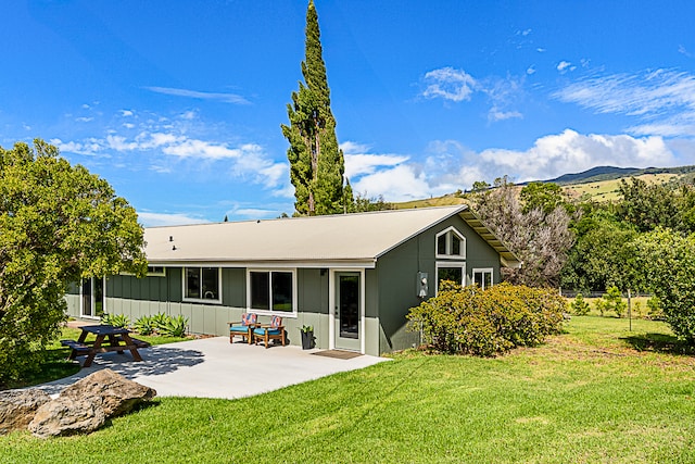 rear view of property featuring a lawn and a patio area