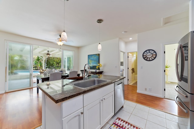 kitchen featuring a kitchen island with sink, sink, light tile patterned flooring, white cabinetry, and stainless steel appliances