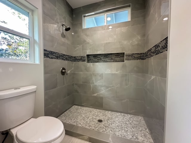 bathroom with toilet and tiled shower