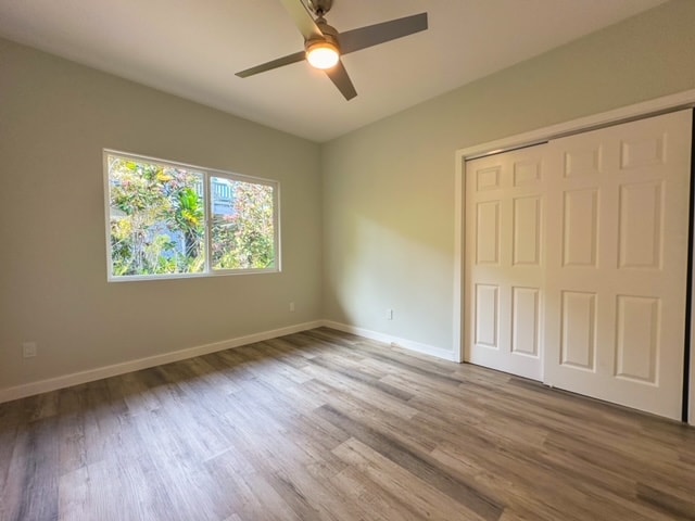 unfurnished bedroom with a closet, hardwood / wood-style flooring, and ceiling fan