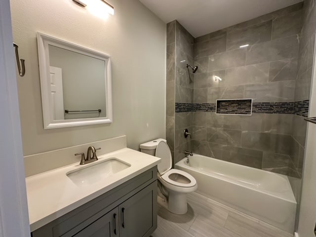 full bathroom featuring vanity, toilet, and tiled shower / bath combo