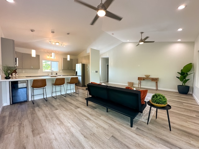 living room featuring light hardwood / wood-style floors, lofted ceiling, wine cooler, and ceiling fan