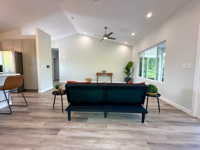 living room featuring vaulted ceiling, light hardwood / wood-style flooring, and ceiling fan