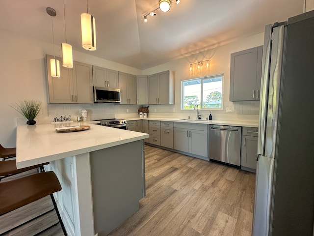 kitchen featuring kitchen peninsula, a kitchen bar, sink, pendant lighting, and stainless steel appliances