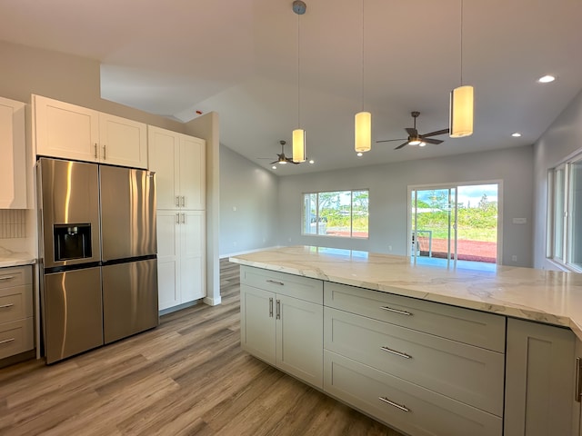 kitchen with light stone countertops, light hardwood / wood-style floors, ceiling fan, pendant lighting, and stainless steel fridge with ice dispenser