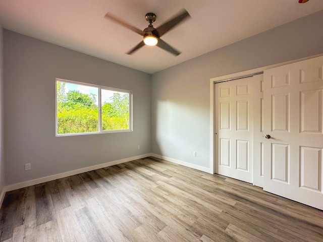 unfurnished bedroom with light hardwood / wood-style flooring, a closet, and ceiling fan