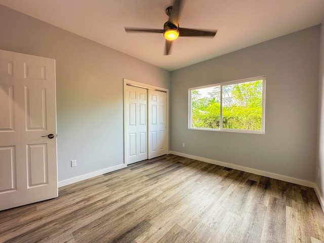 unfurnished bedroom with light hardwood / wood-style flooring, a closet, and ceiling fan