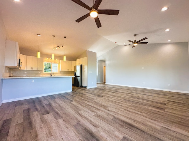 kitchen with hanging light fixtures, vaulted ceiling, white cabinets, hardwood / wood-style flooring, and stainless steel fridge with ice dispenser