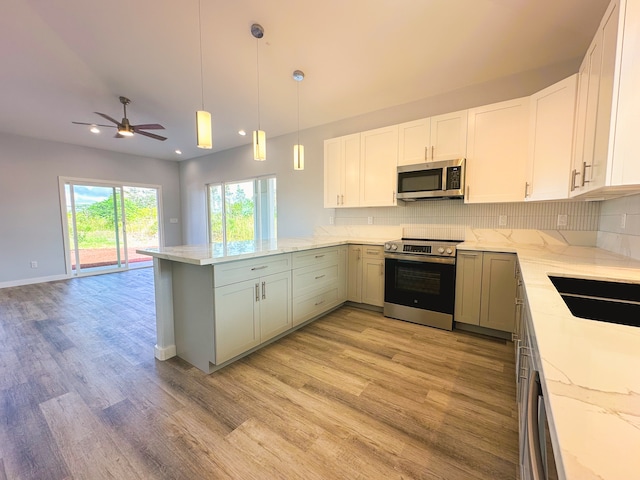 kitchen with appliances with stainless steel finishes, light hardwood / wood-style flooring, kitchen peninsula, and white cabinets