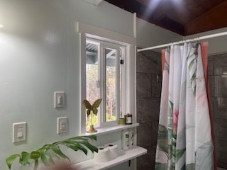 bathroom with walk in shower and vaulted ceiling