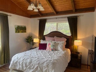 bedroom featuring wood-type flooring, vaulted ceiling with beams, wood ceiling, and an inviting chandelier